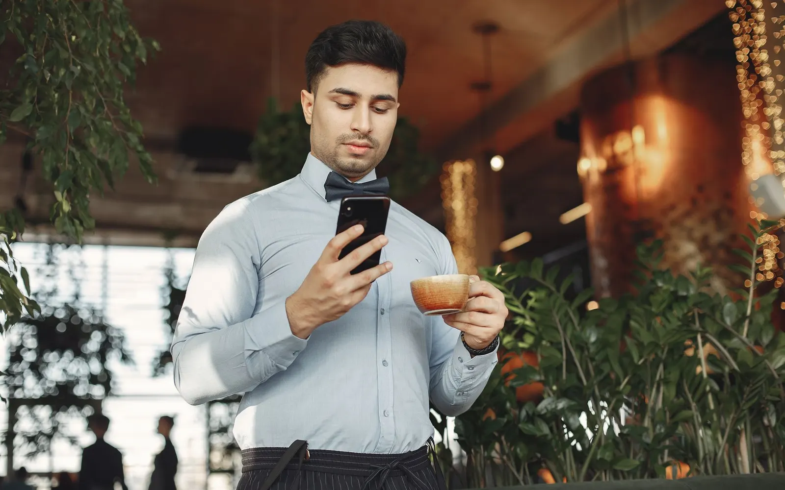 A person reading an email on their phone with a coffee