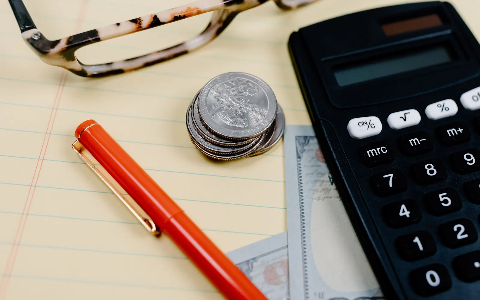 A calculator and money on a desk, working out costs