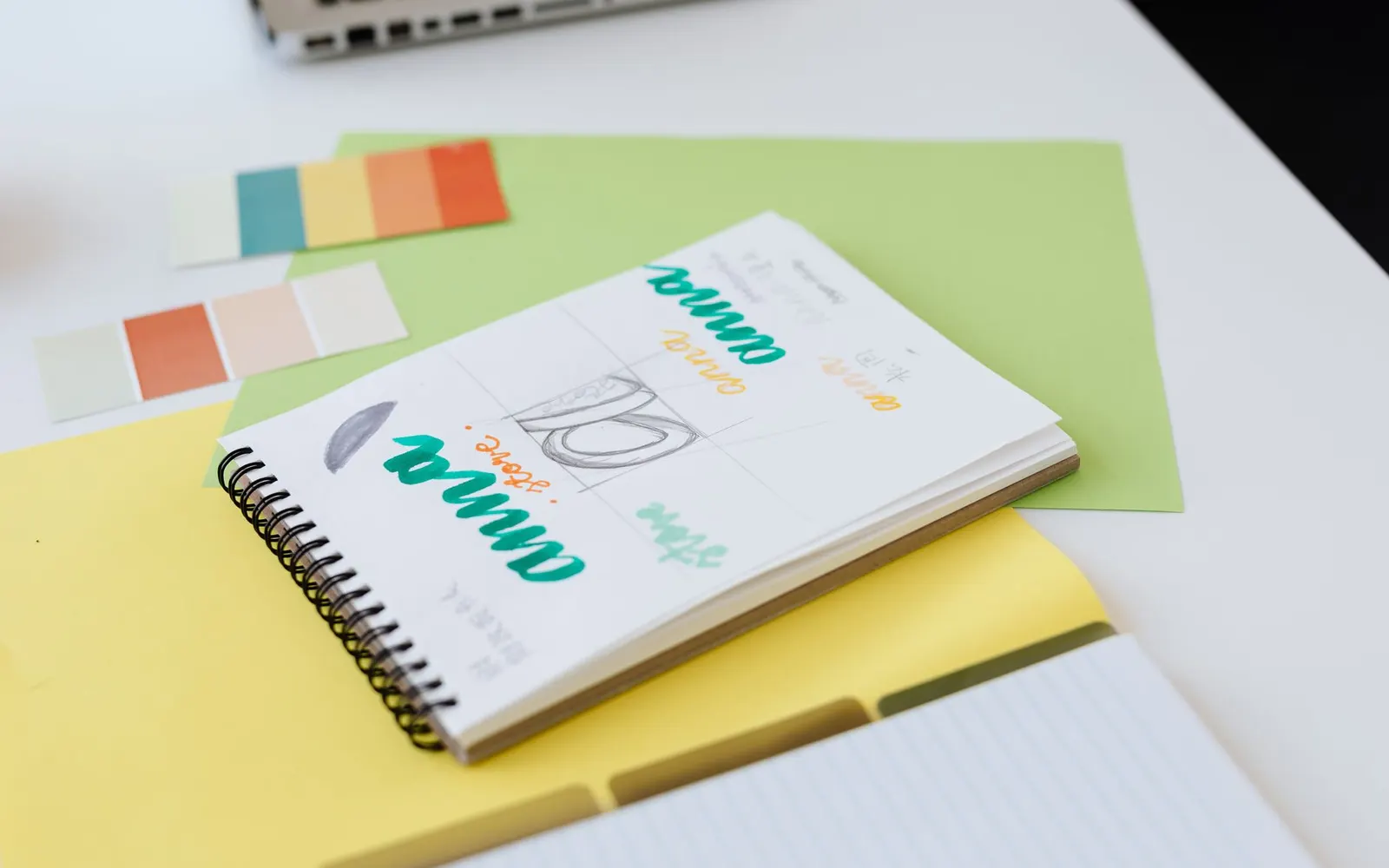 A notebook with hand-drawn logo lettering next to color swatches