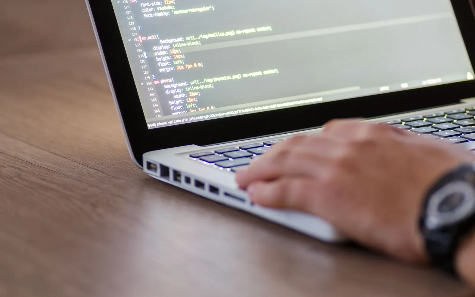 Developer writing code on a laptop with charts on screen